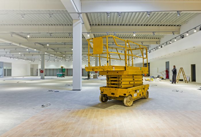 Scissor lift platform is inside of new big hall in building process.